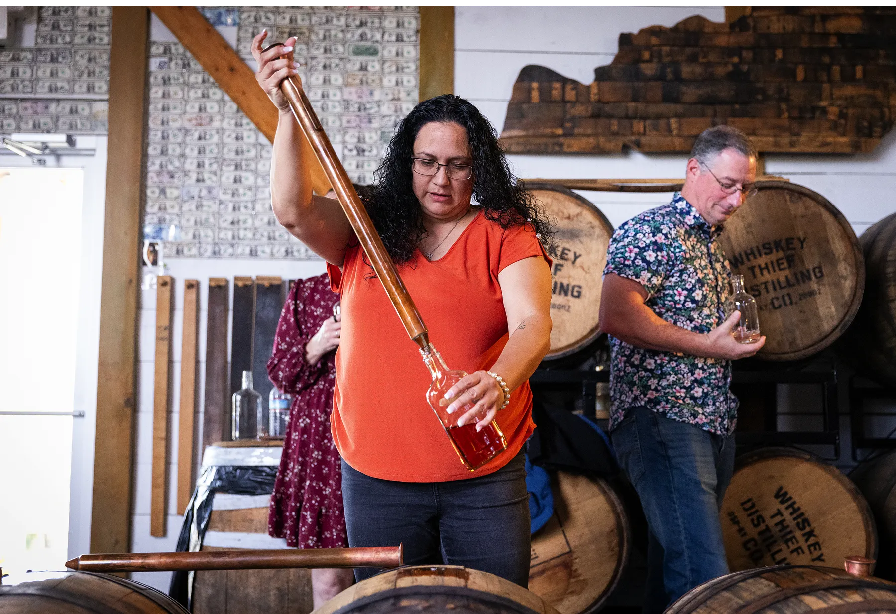 Customer using the traditional distiller's tool to fill their own bottle of bourbon.