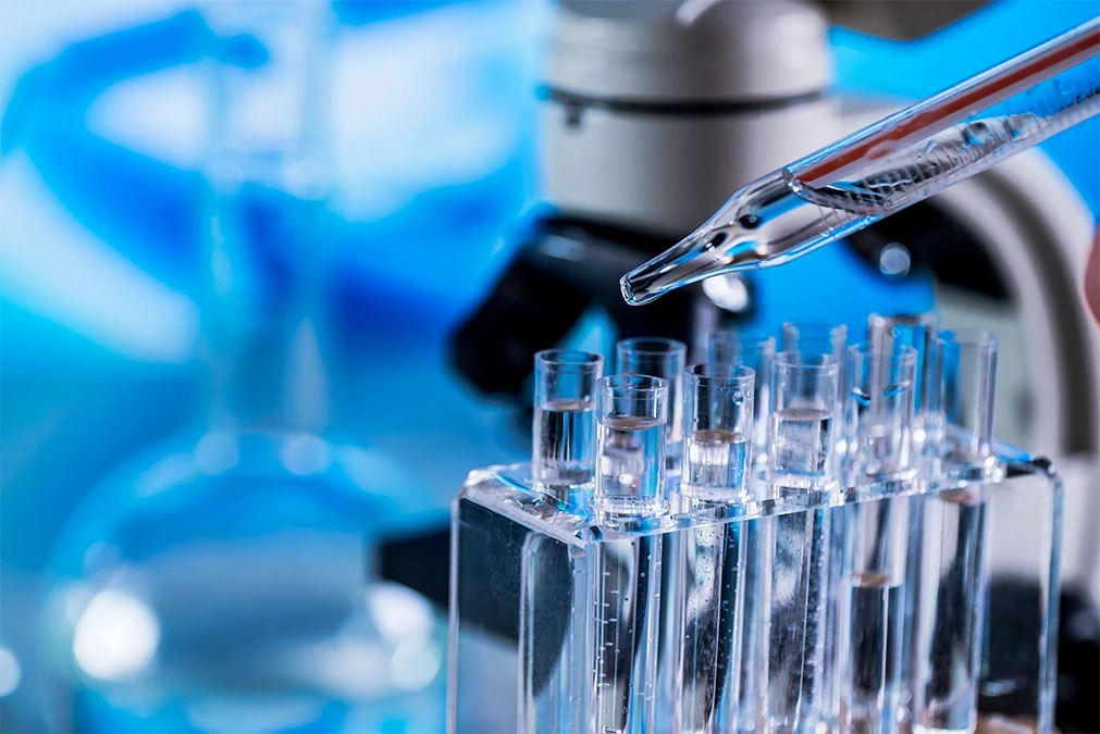 Close-up of a dropper over test tubes in a lab setting, highlighting forensic or medical testing for chemical and industrial burns