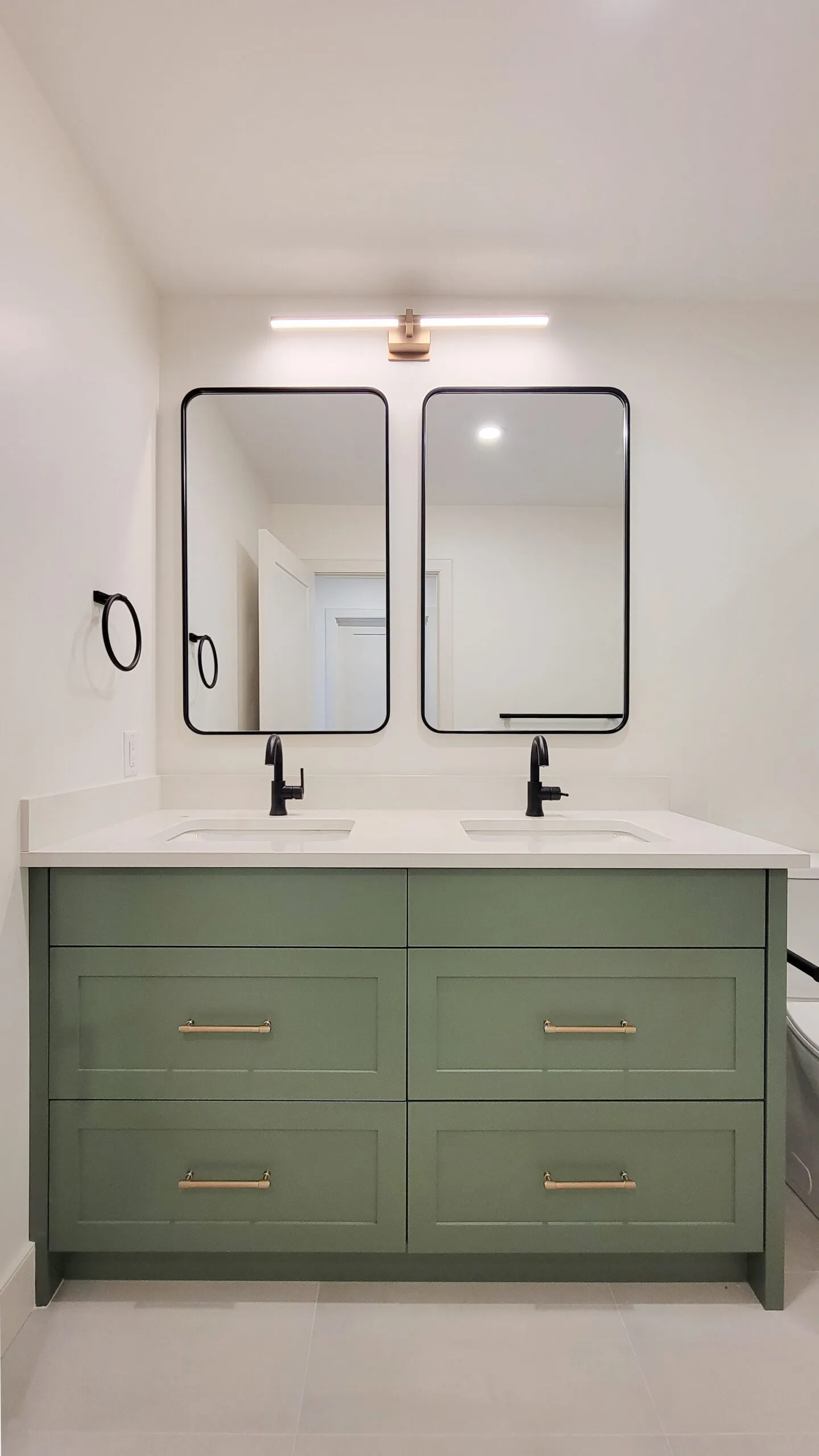 Image of dual vanity with green millwork and white countertop.