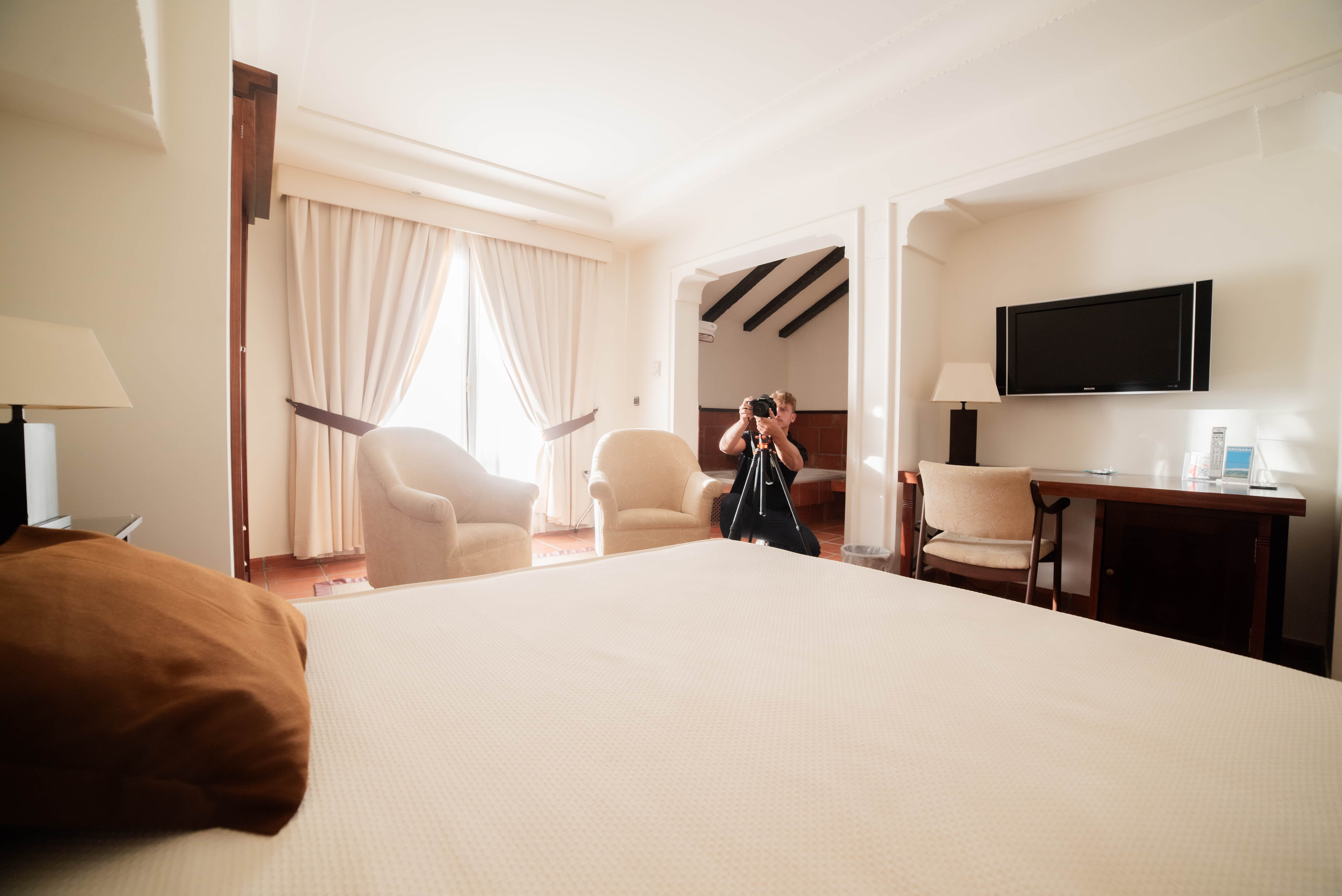 person taking picture of a light and modern bedroom