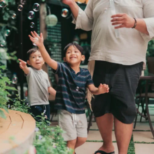 Two young brothers reaching for bubbles outdoors, representing pediatric care for families in Melbourne's inner north.