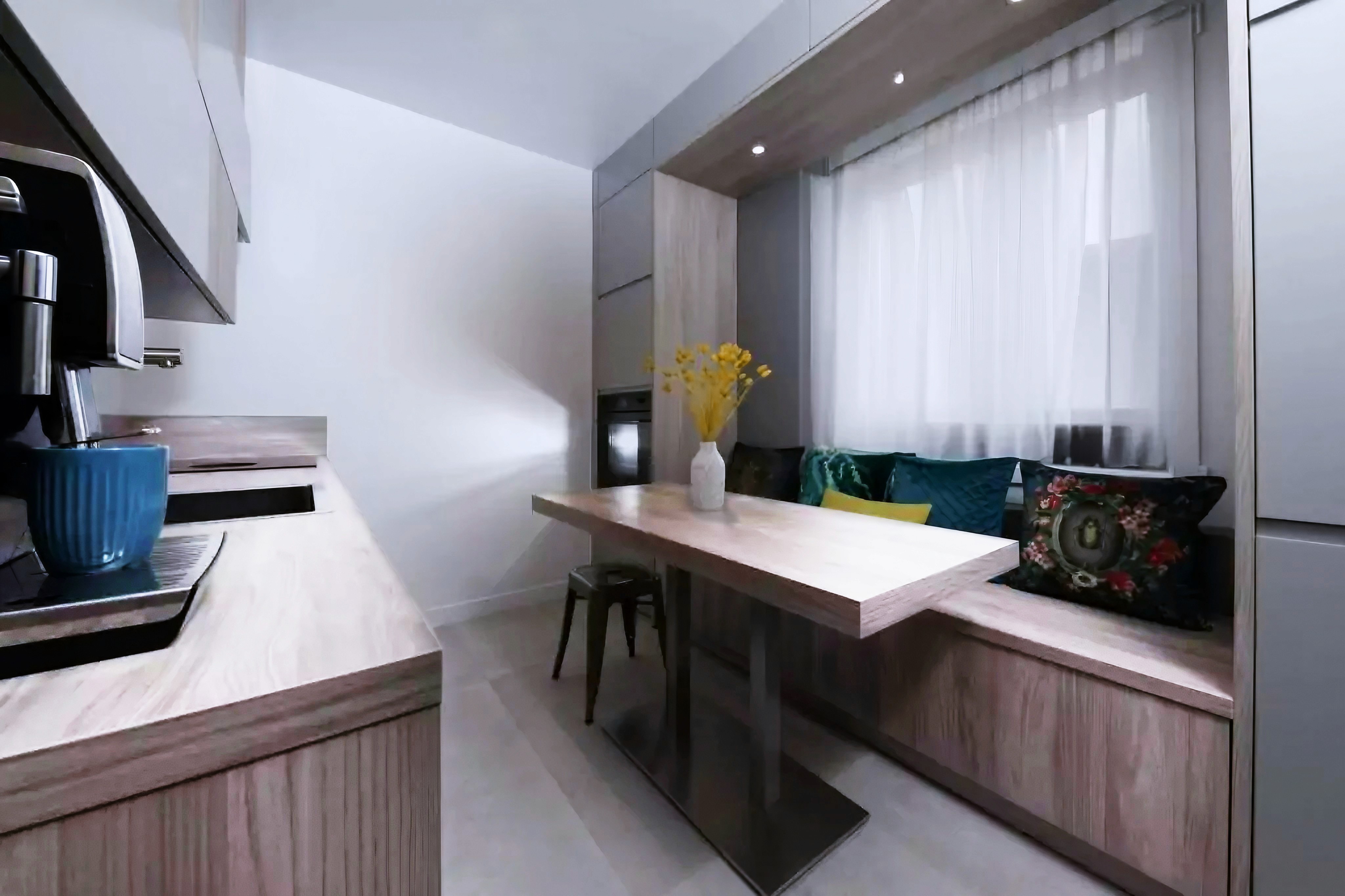 Rénovation cuisine 77 avec armoires et comptoirs bois clair, banc encastré avec coussins colorés et table rectangulaire, architecte d'intérieur.