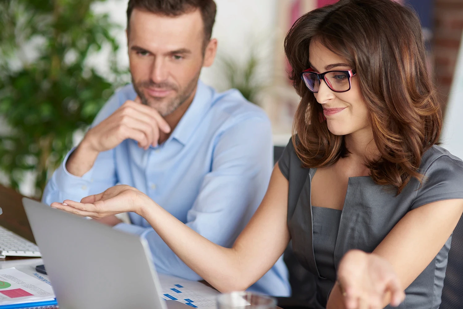 Smiling woman and satisfied man looking at a computer screen together in an office.