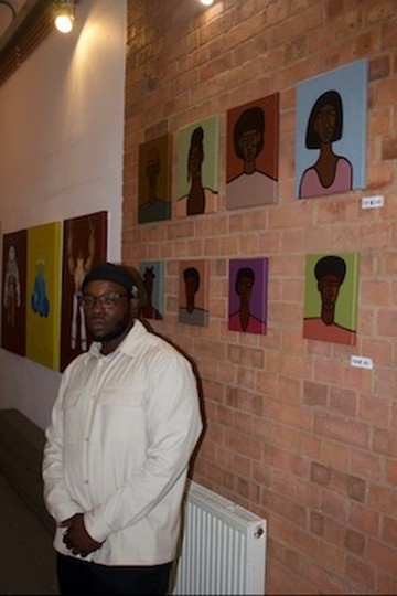 Portrait beside artworks presented on the brick wall