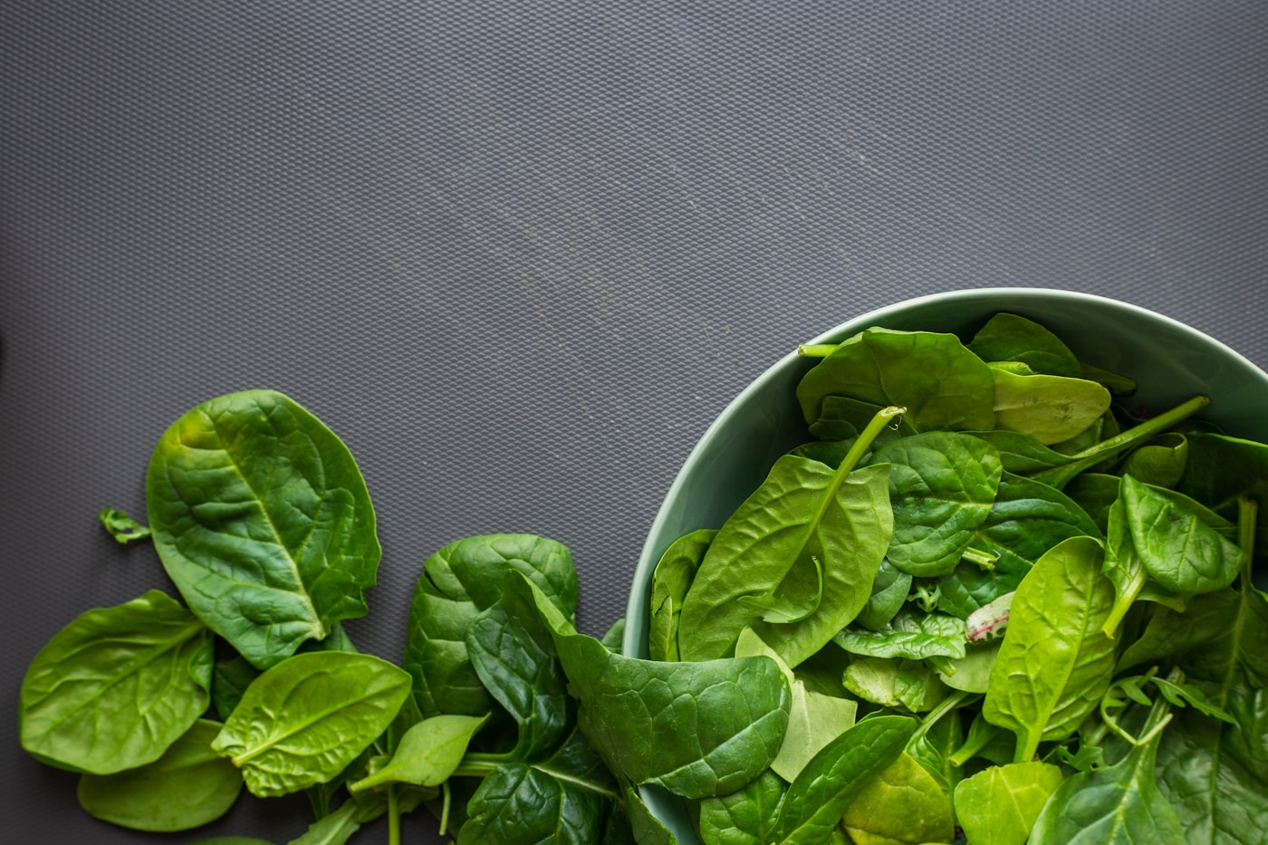 Fresh spinach leaves in a bowl, an iron-rich leafy green for menstruating athletes