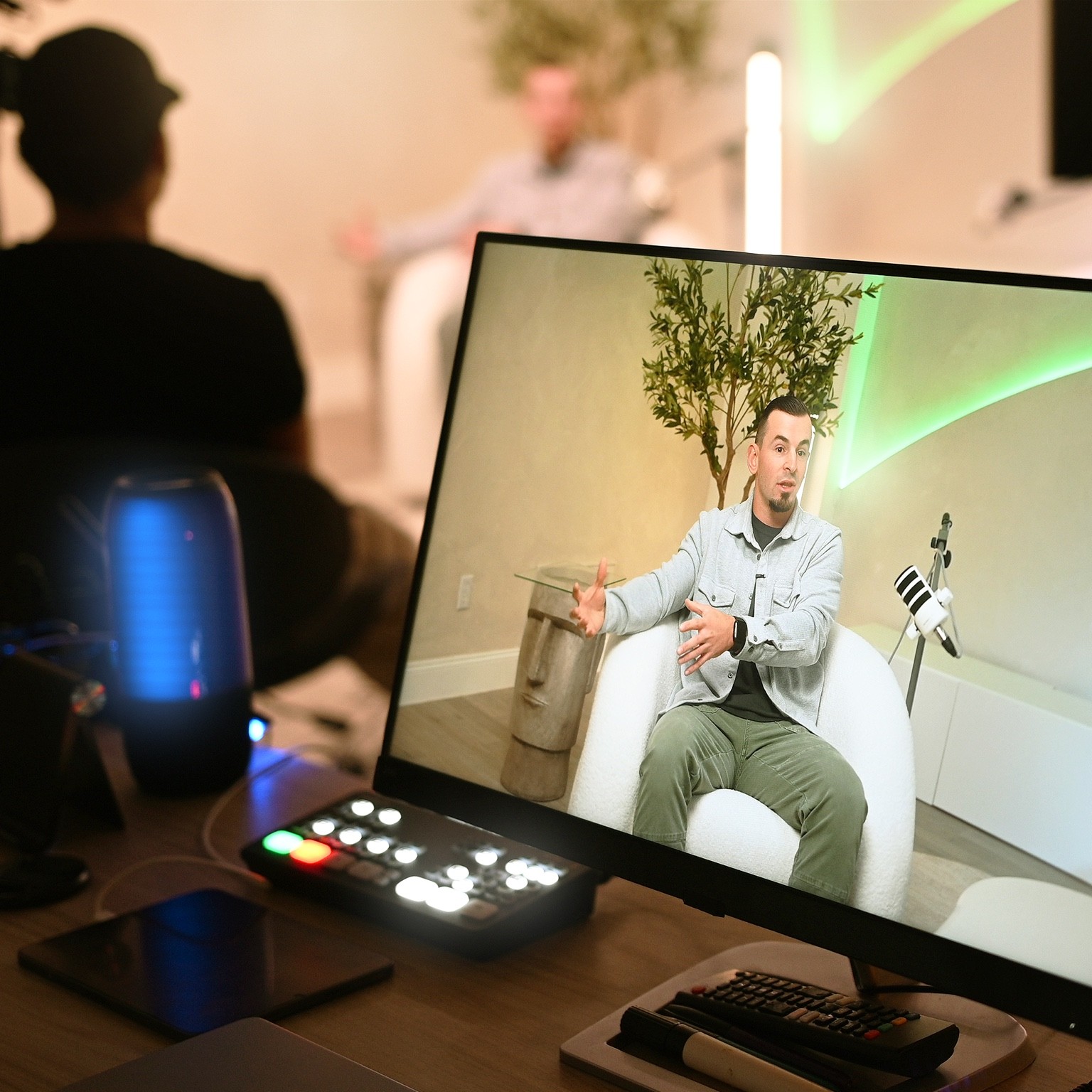 The production monitor shows a guest on camera against green accent lighting.