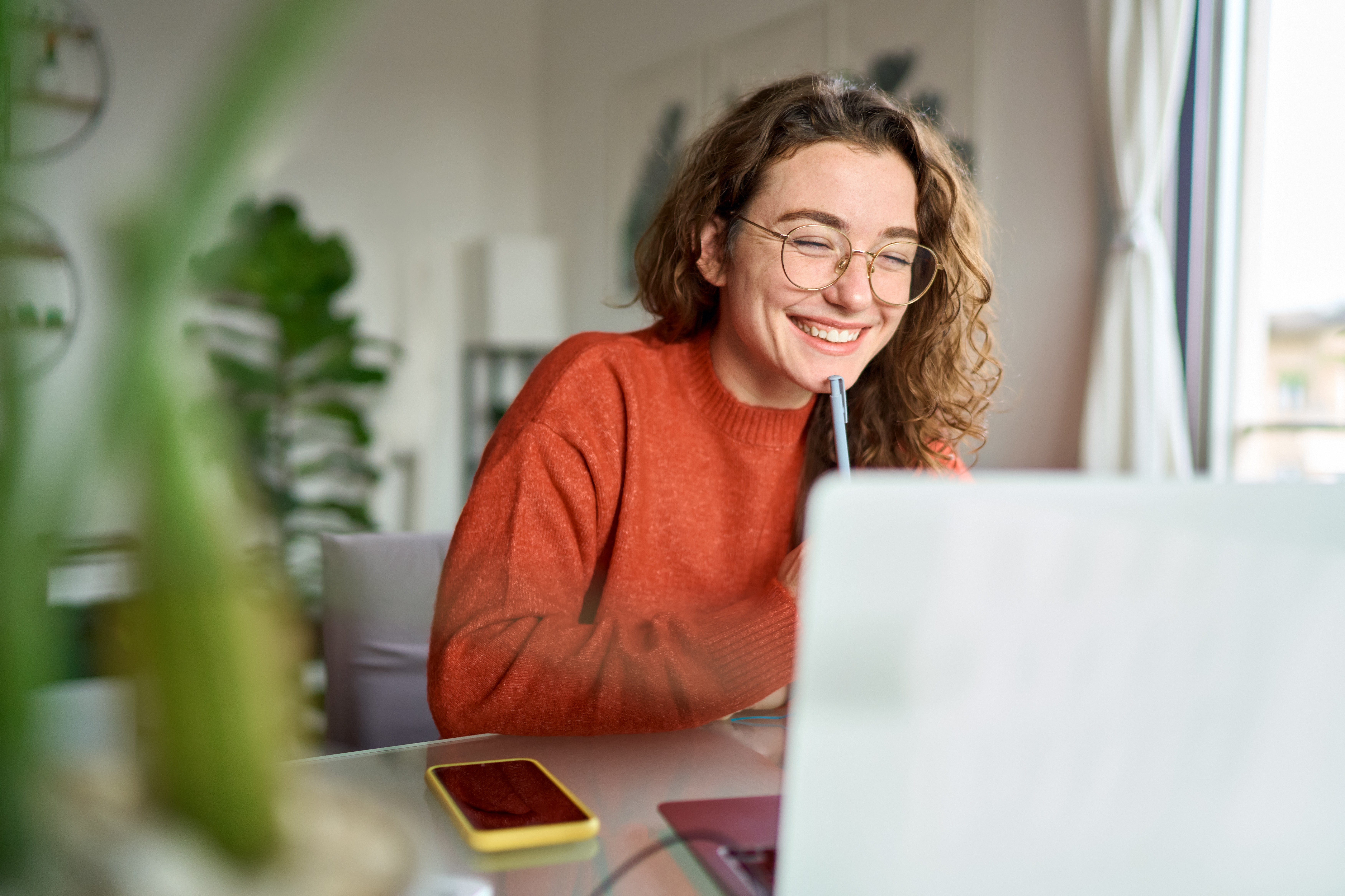 A smiling woman works on a laptop.