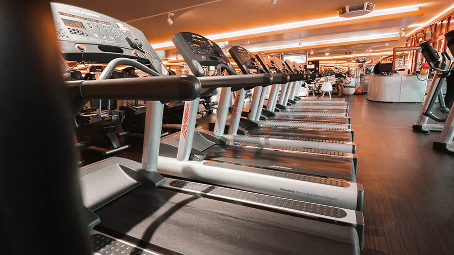 Large house with a wrap-around balcony overlooking a lit pool and deck at night.