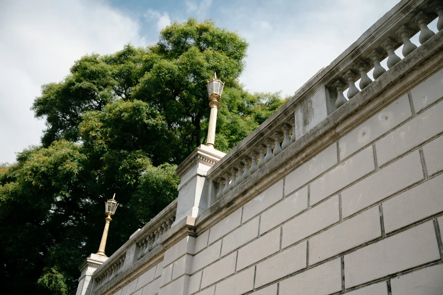 Pared de piedra histórica con farolas clásicas y árboles en el barrio Atrium La Isla.