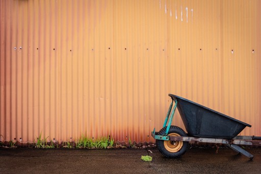 Authentic winery image of a weelbarrow and orange corrugated iron wall