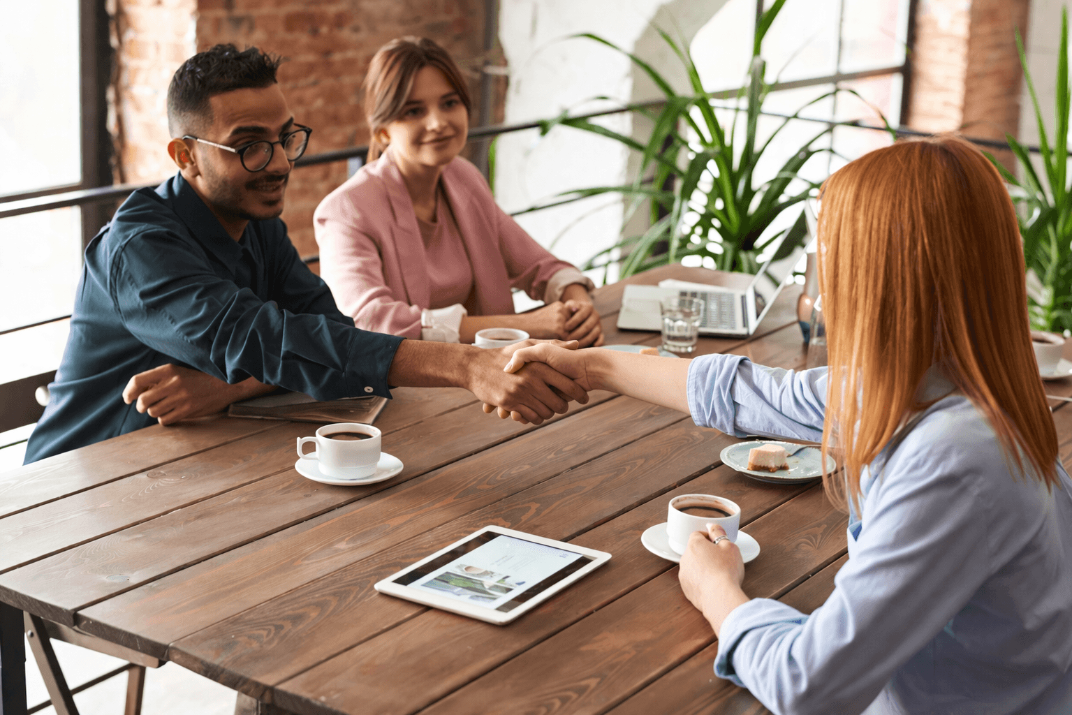 Small business owner at repair shop interacts with a customer, illustrating communications and customer engagement with a business phone system.