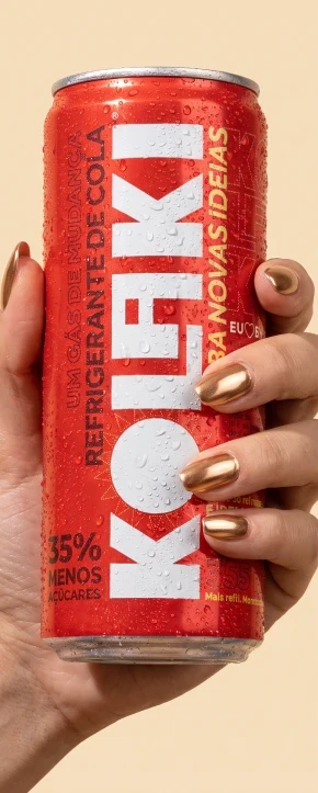 Mão com unhas douradas segurando uma lata gelada de Kolaki