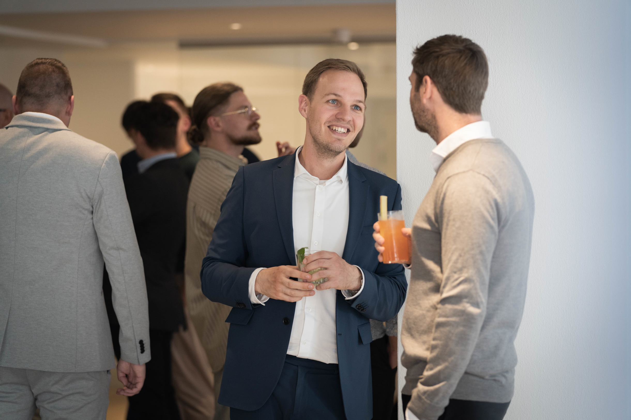 Lab technician in protective gear using a high-tech analyzer while referencing data on dual computer screens in a laboratory setting.