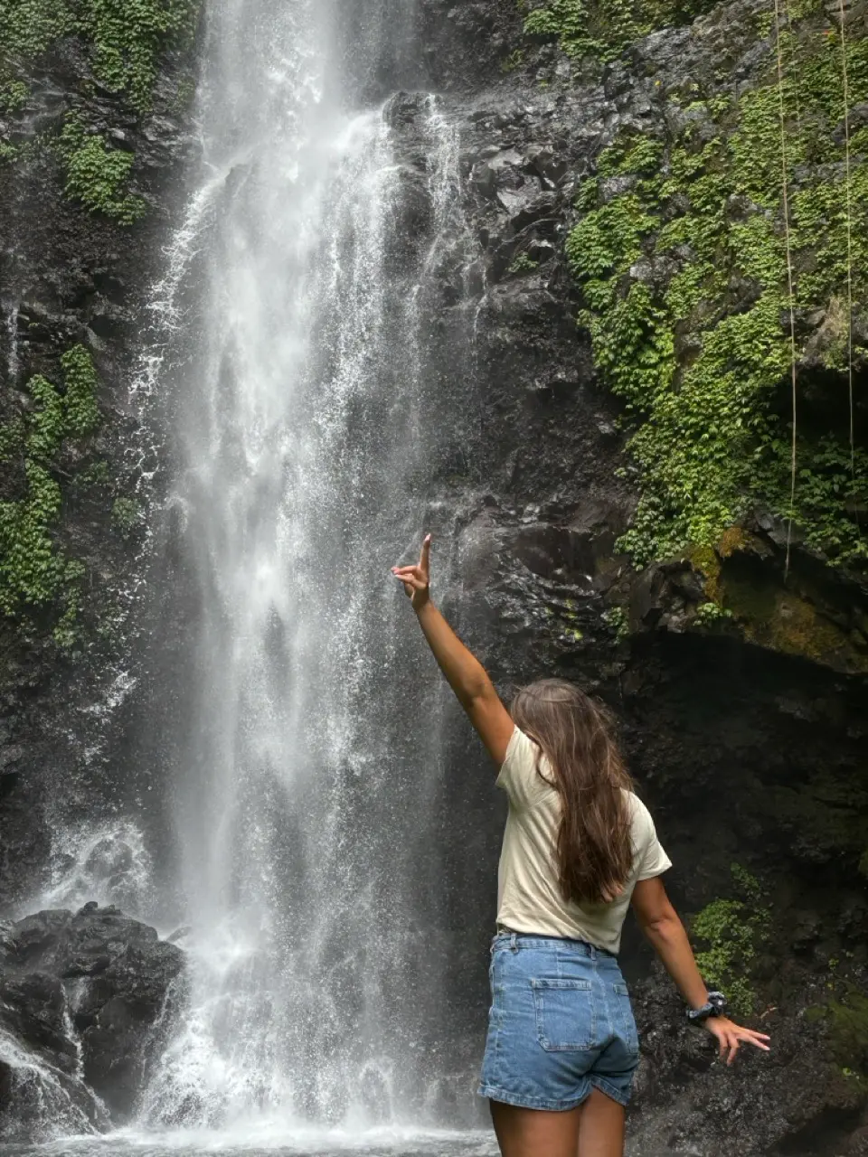 een vrouw met gespreidde armen voor een waterval