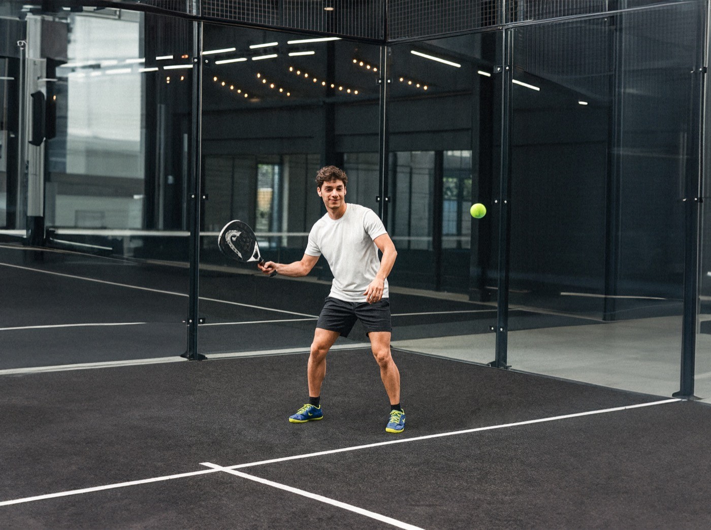 Padelspieler in weissem Shirt bereitet sich auf den Ballwechsel vor – Fokus, Bewegung und Spielfreude auf dem schwarzen Padelnero Court.