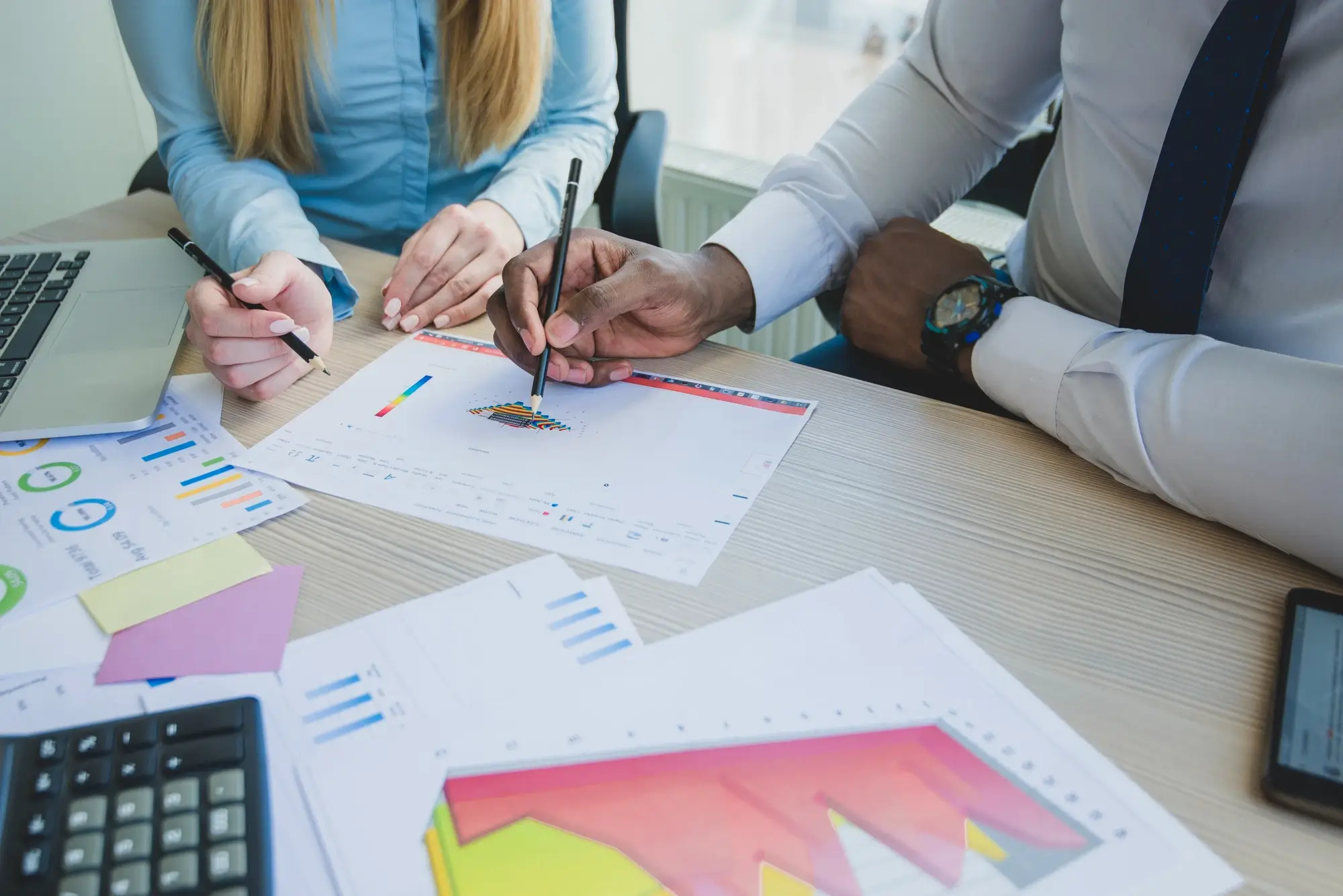 Ofiste grafik ve raporları inceleyen iki çalışan.