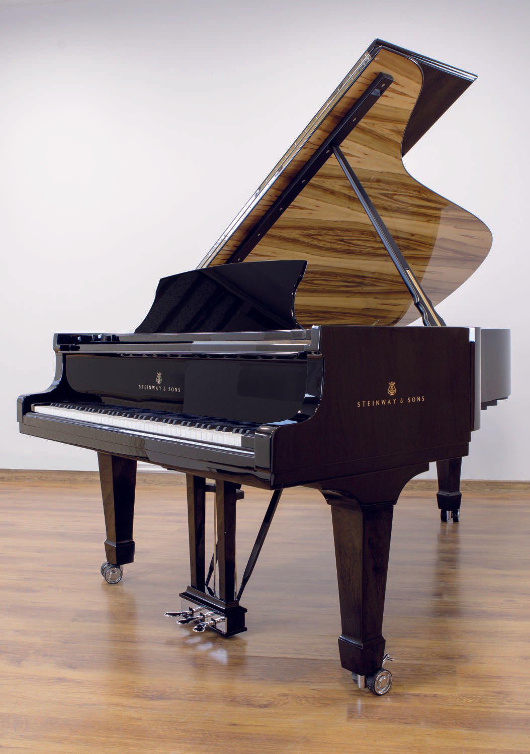 A fully restored Steinway & Sons grand piano with a polished black polyester finish and amberwood accents, standing in a bright showroom.