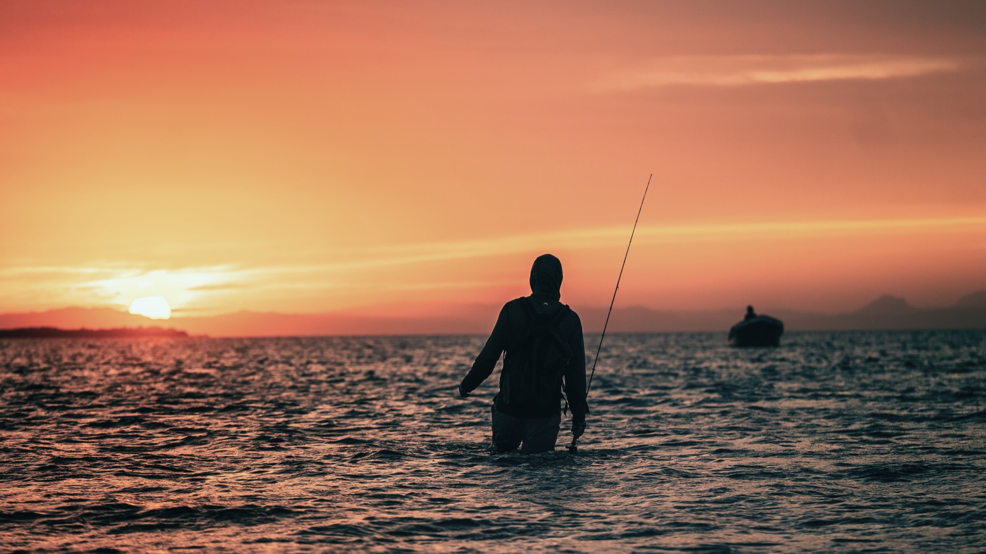 Saltwater angler walking towards the skiff during sunset outside Placencia