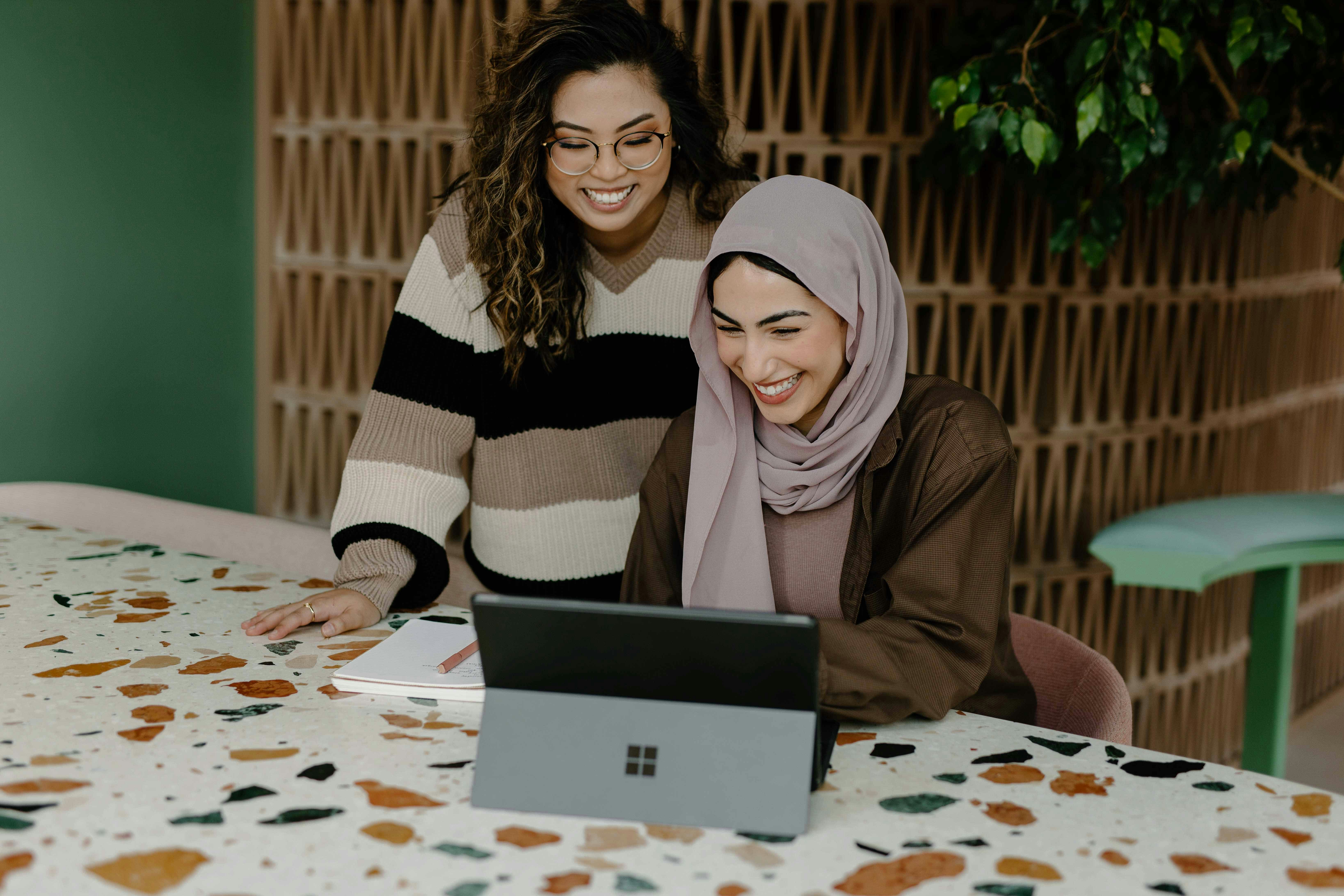 To kvinder smiler mens de kigger på en computer