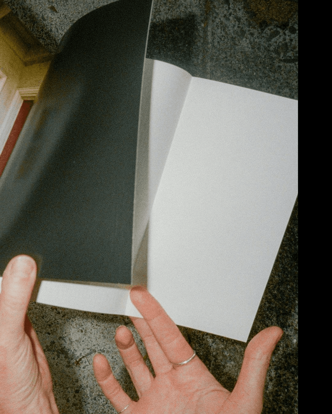 A hand opening a notebook with blank white pages.