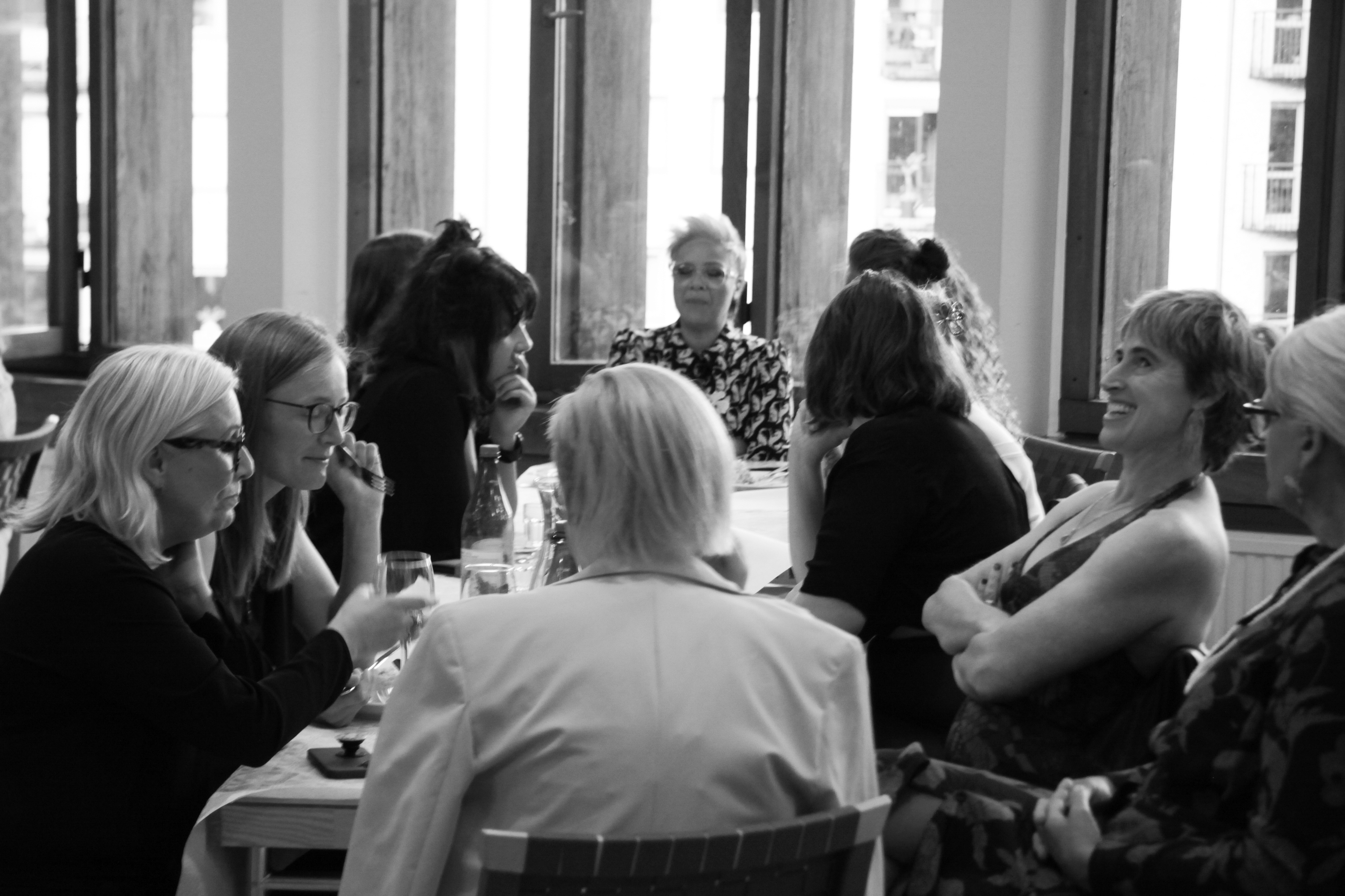 A group of people chatting and laughing at a dining table.