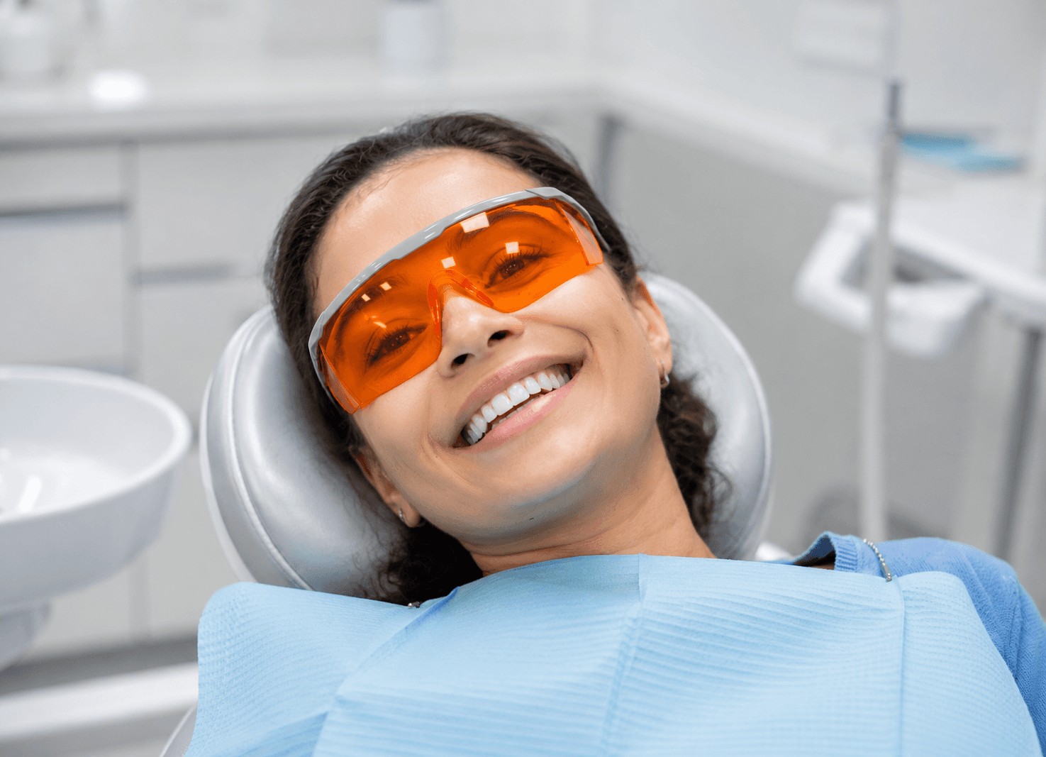 Patient wearing protective orange eyewear during minimally invasive laser dentistry recovery procedure. 