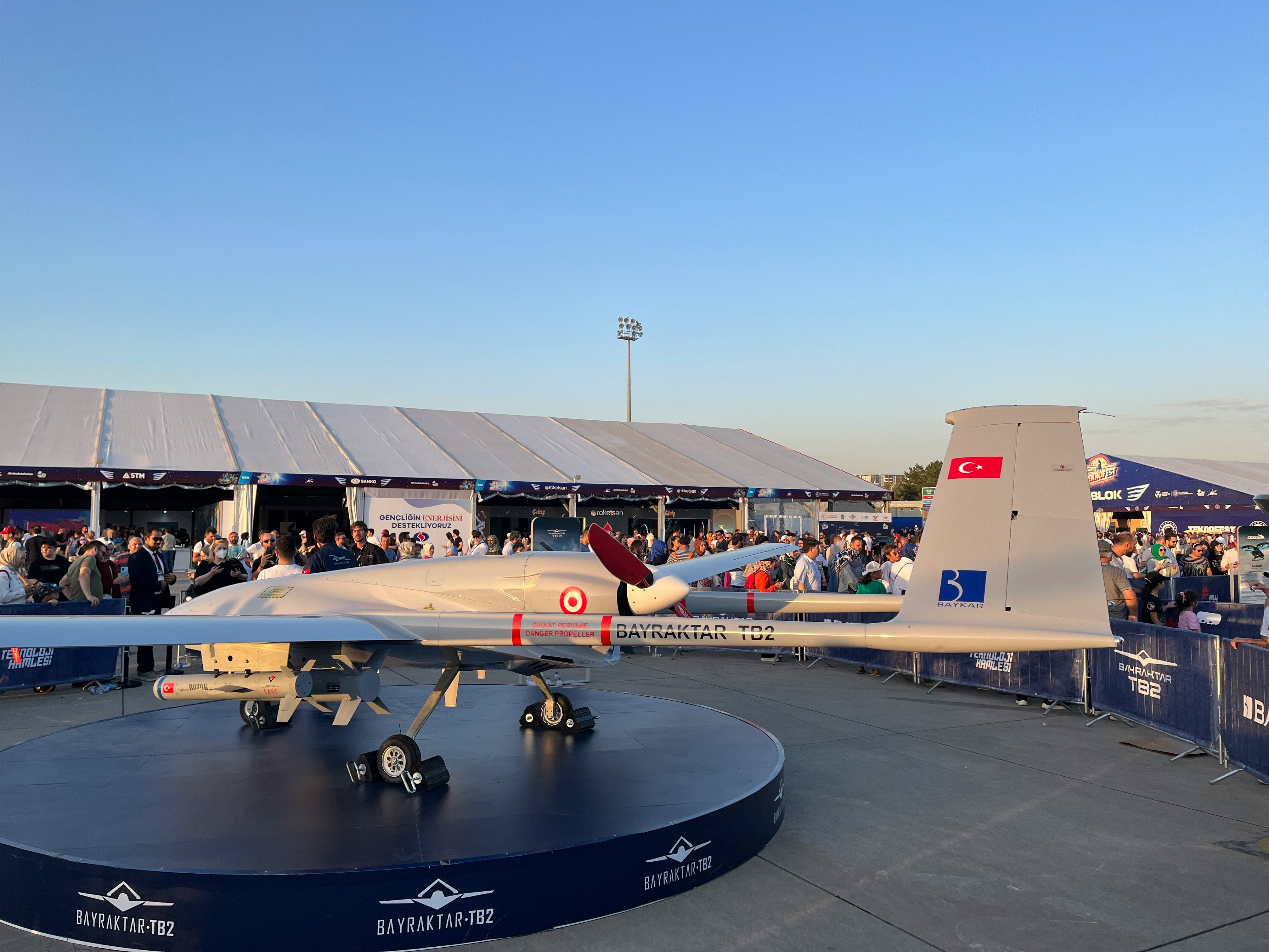 a crowd of people standing around a plane on display