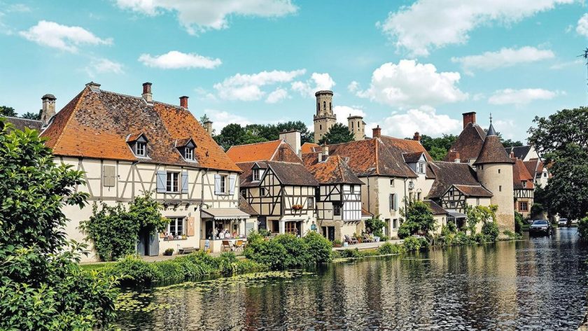 Vue pittoresque d'une ville historique en France, bordée par une rivière. Architecture médiévale.