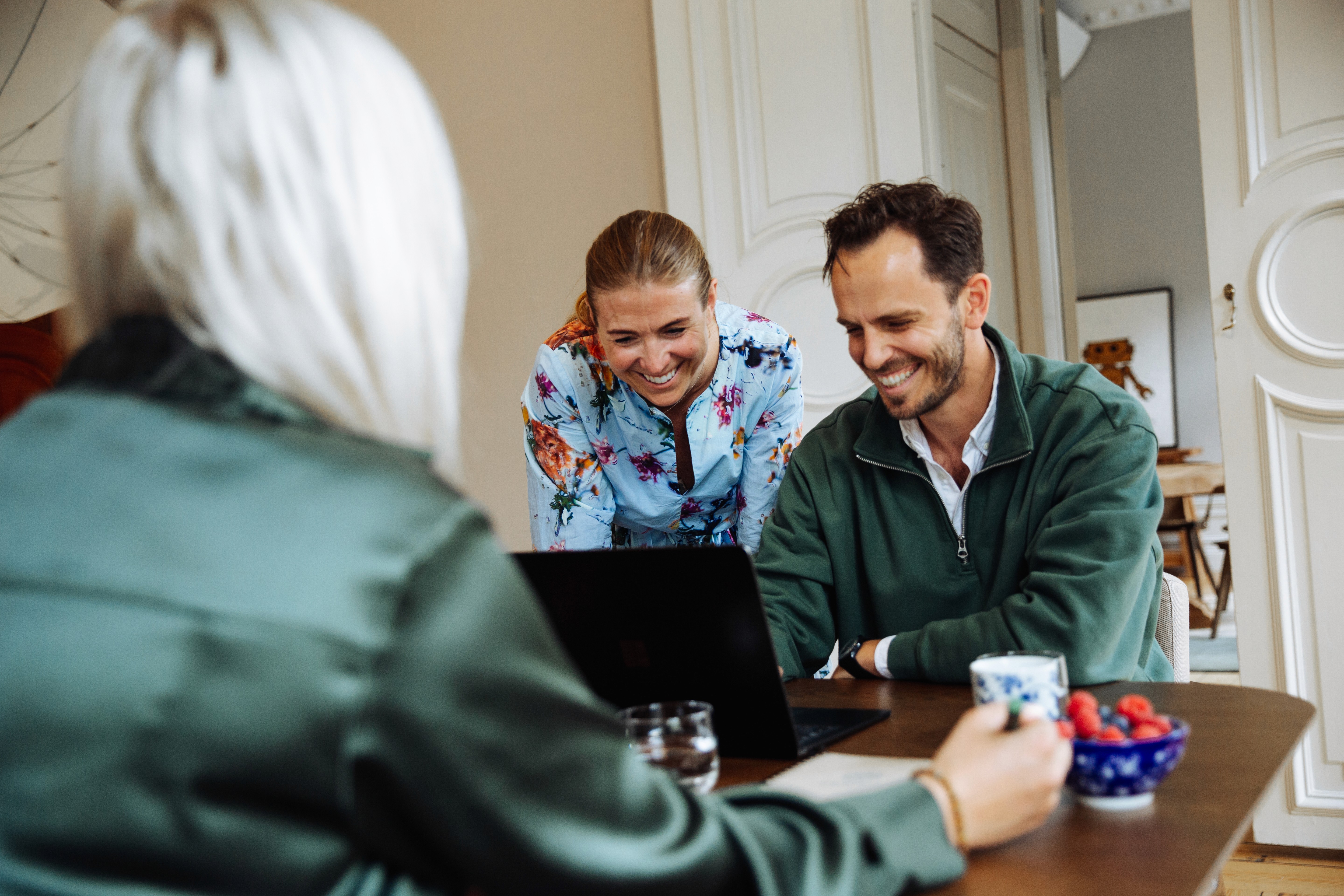 a group of people sitting around a table with laptops