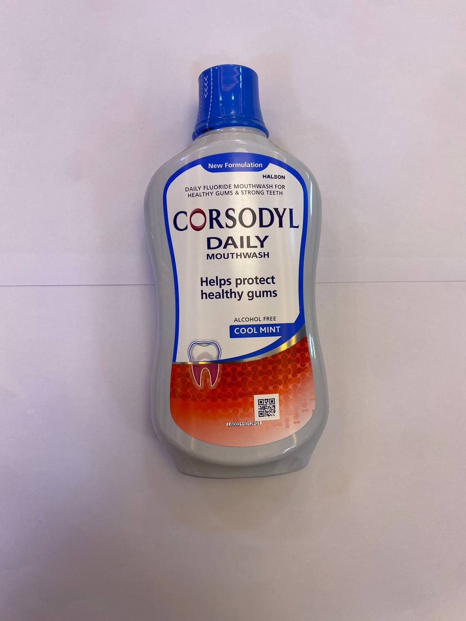 A dark brown plastic bottle with a white cap and red label text stands upright against a plain white background.