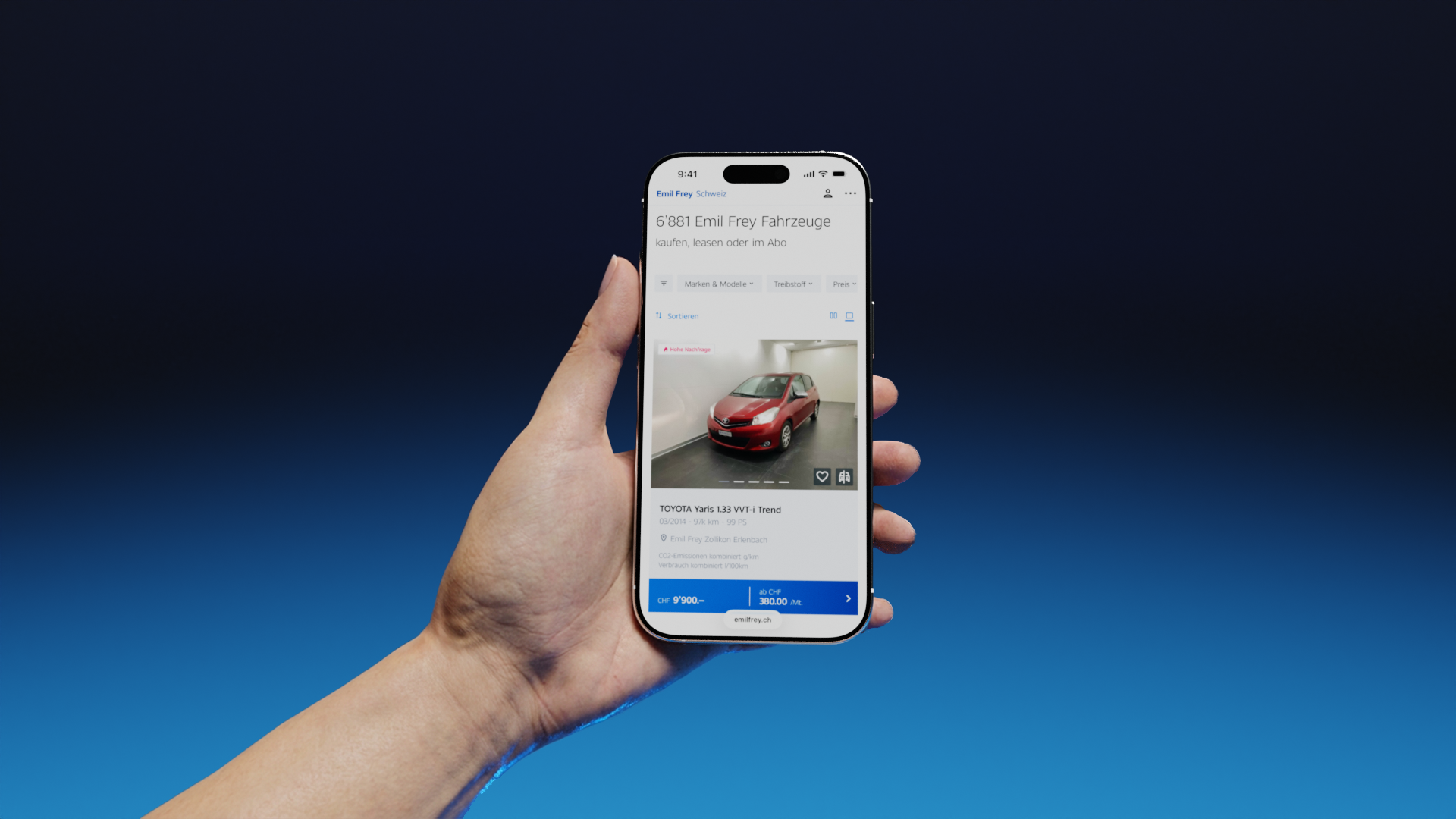 Eine Hand, die ein Smartphone hält, auf dem die Website von Emil Frey Switzerland und ein zum Kauf oder Leasing verfügbares Automodell zu sehen sind. 
