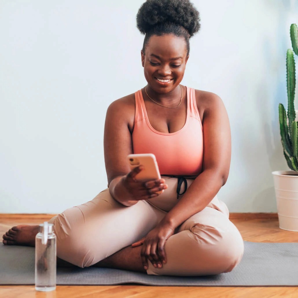Woman smiling holding phone with provider on screen and a compounded semaglutide bottle next to her.