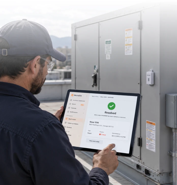 HVAC technician using a tablet beside rooftop units