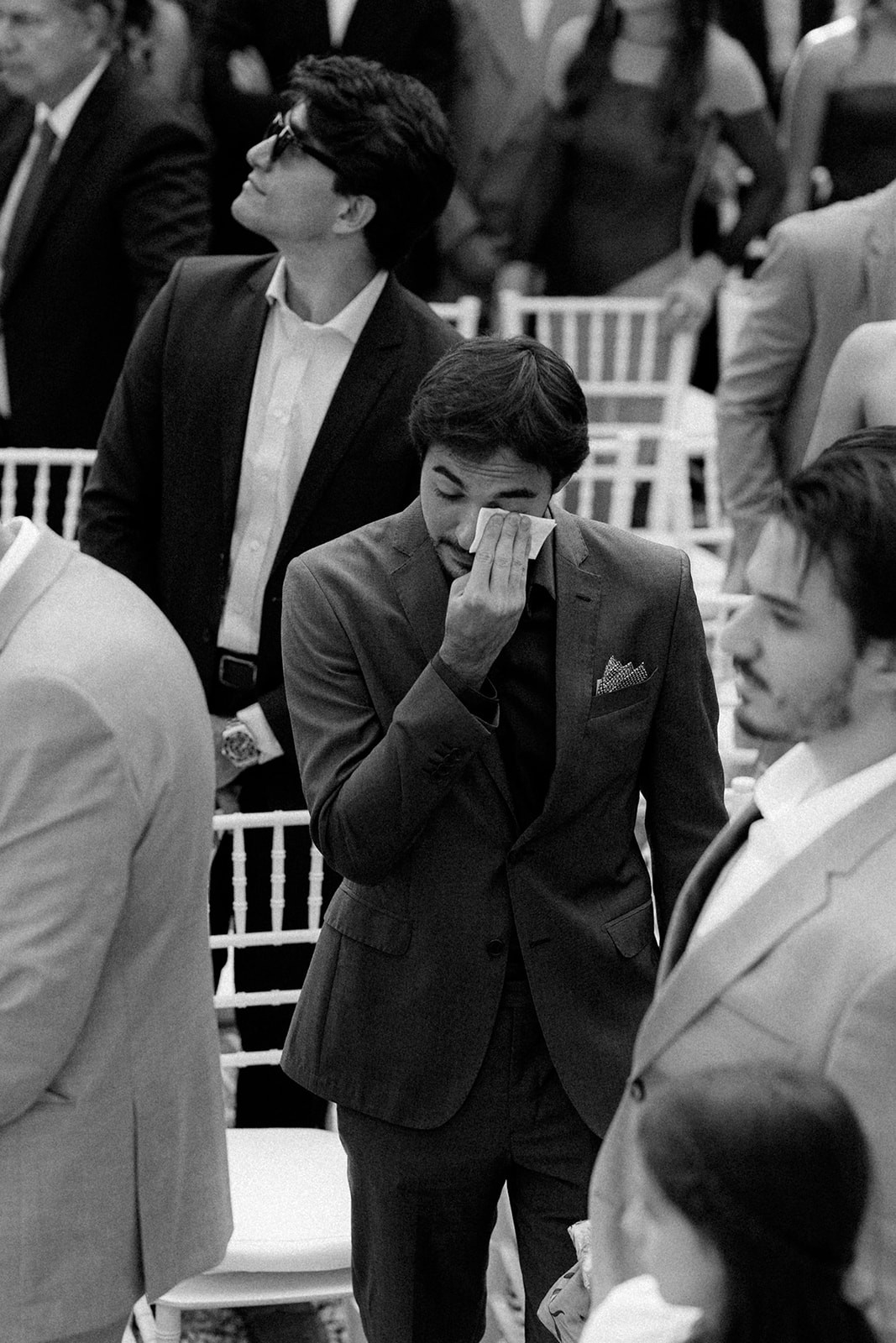 A couple embraces and kisses during their wedding ceremony, captured in a black and white photo.