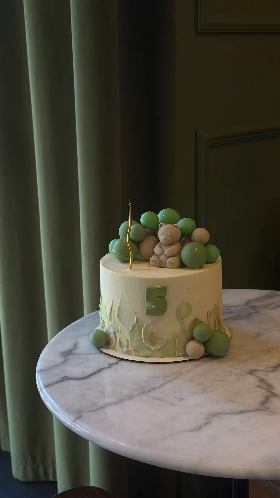 White frosted carrot cake with green and beige macarons on top and "HOME" branding