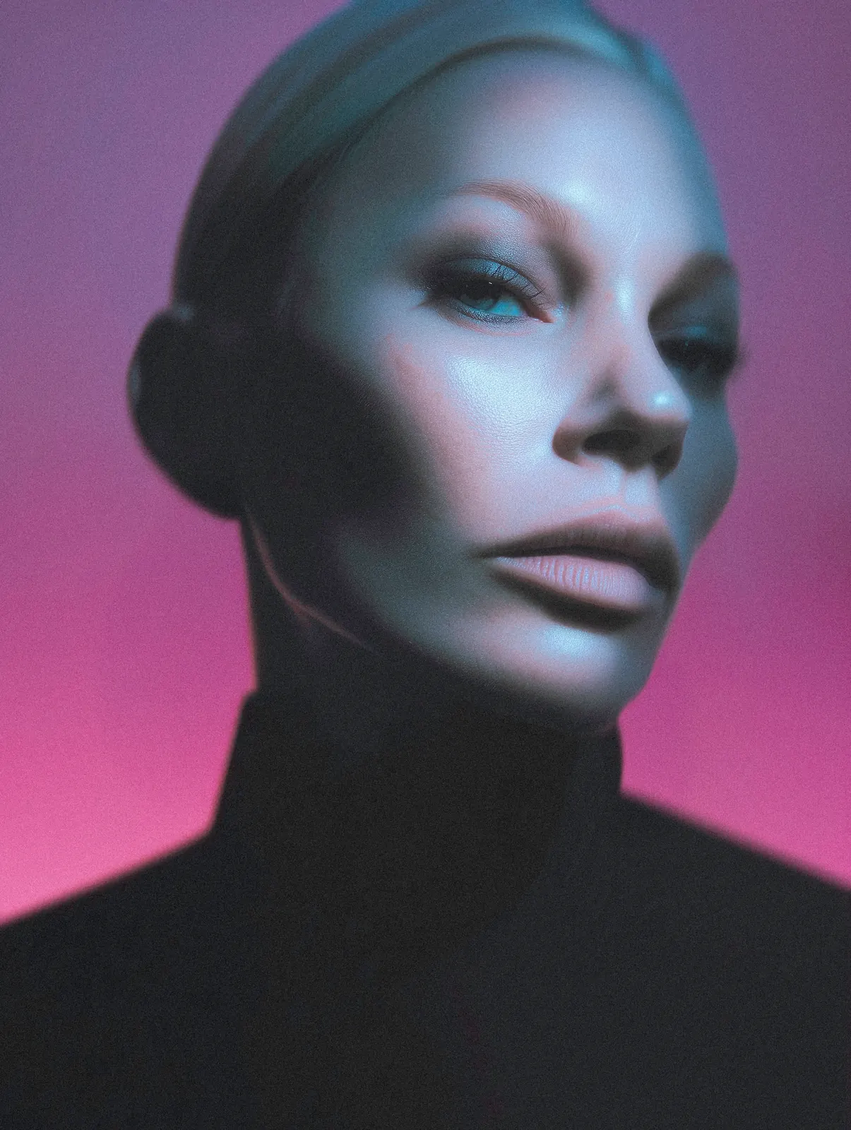 Close-up portrait with a shaved head in violet and pink studio lighting.