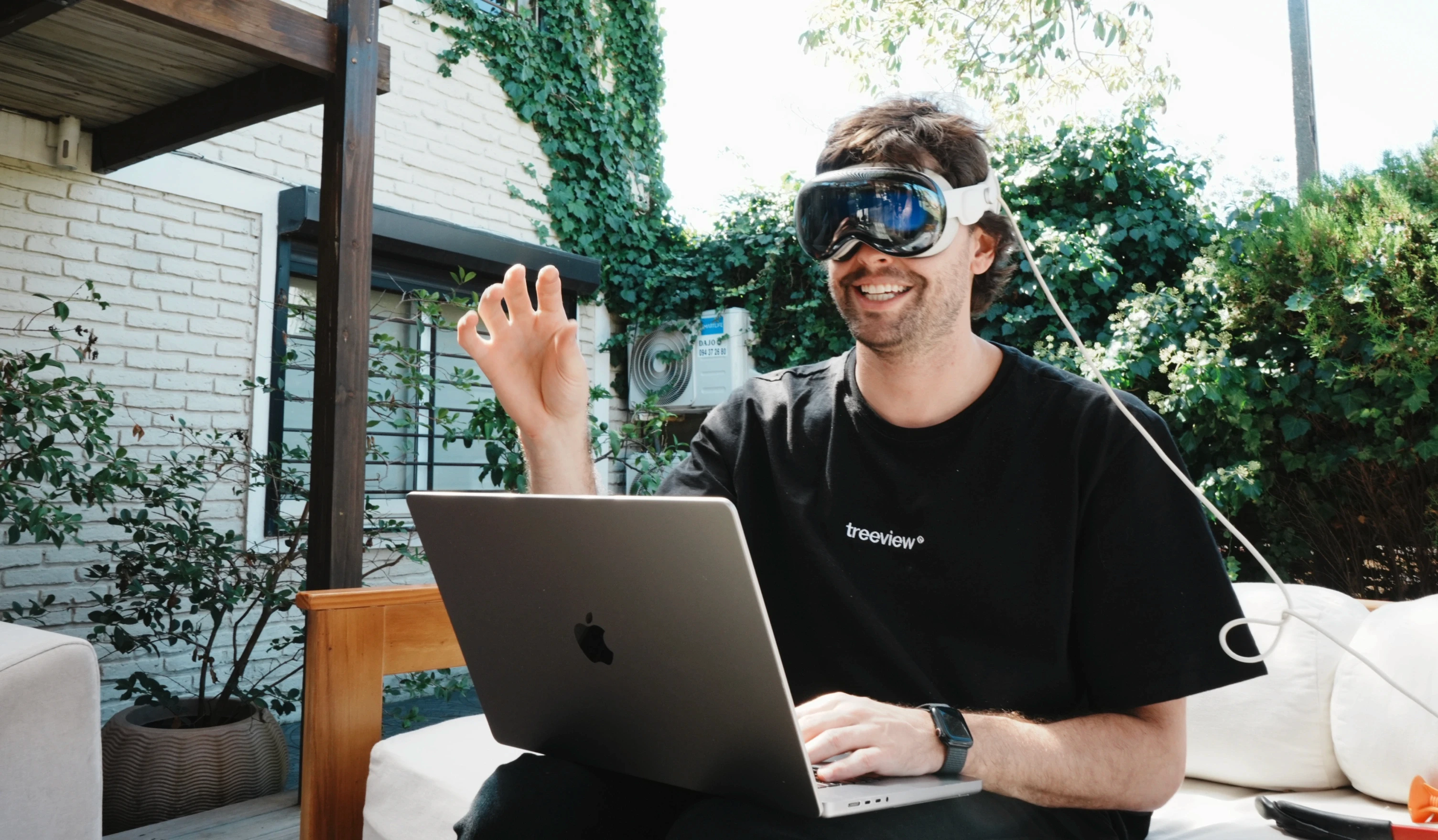 Treeview founder Horacio Torrendell wearing Apple Vision Pro and using hand gesture input while working on a MacBook outdoors