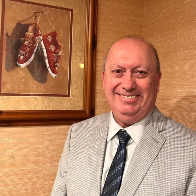 Confident woman with long curly hair wearing sunglasses and a shimmering top, photographed from a low angle against a deep blue sky.