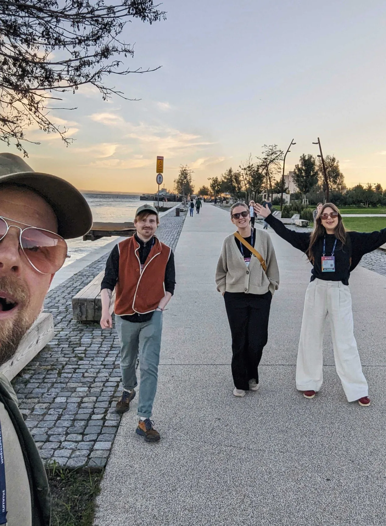 Fyra personer med konferensbrickor på en strandpromenad i solnedgång