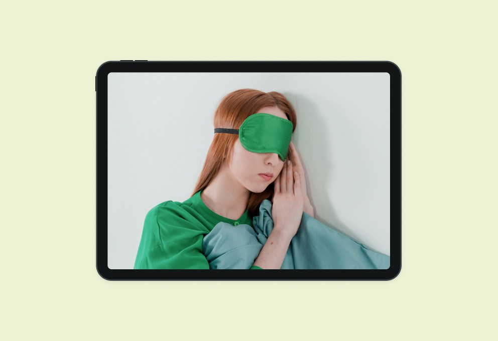 A mockup of a phone displaying an image of a woman sleeping and wearing a face mask