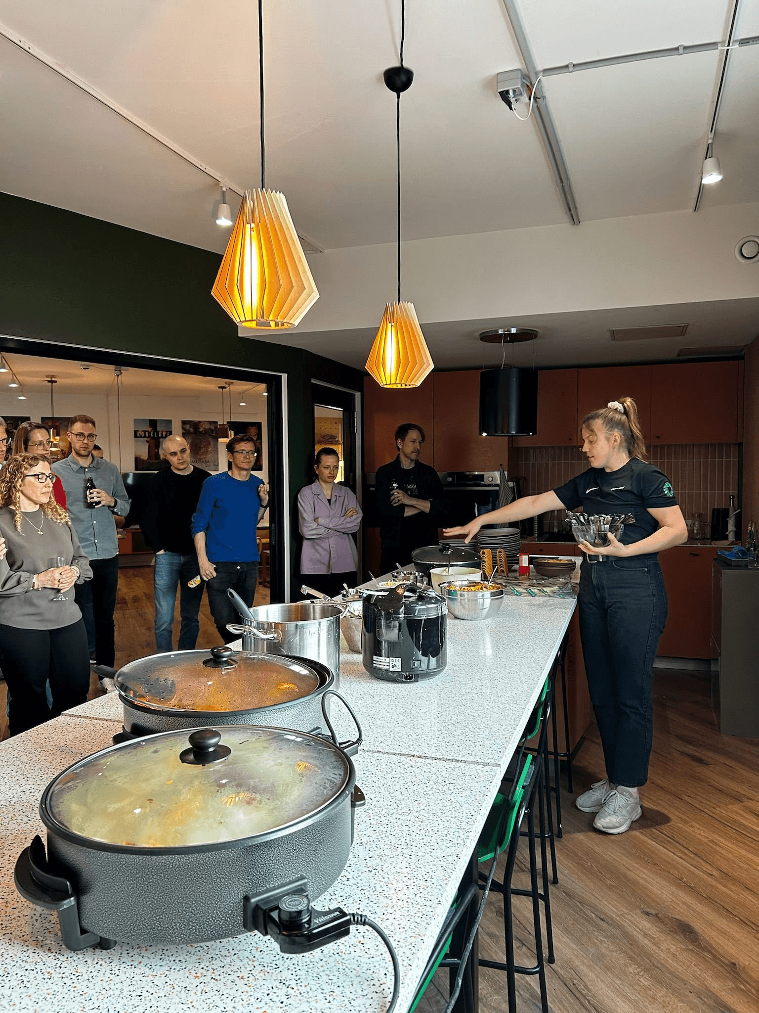 Ein Essensbuffet mit Töpfen und einige junge Menschen sind im Hintergrund