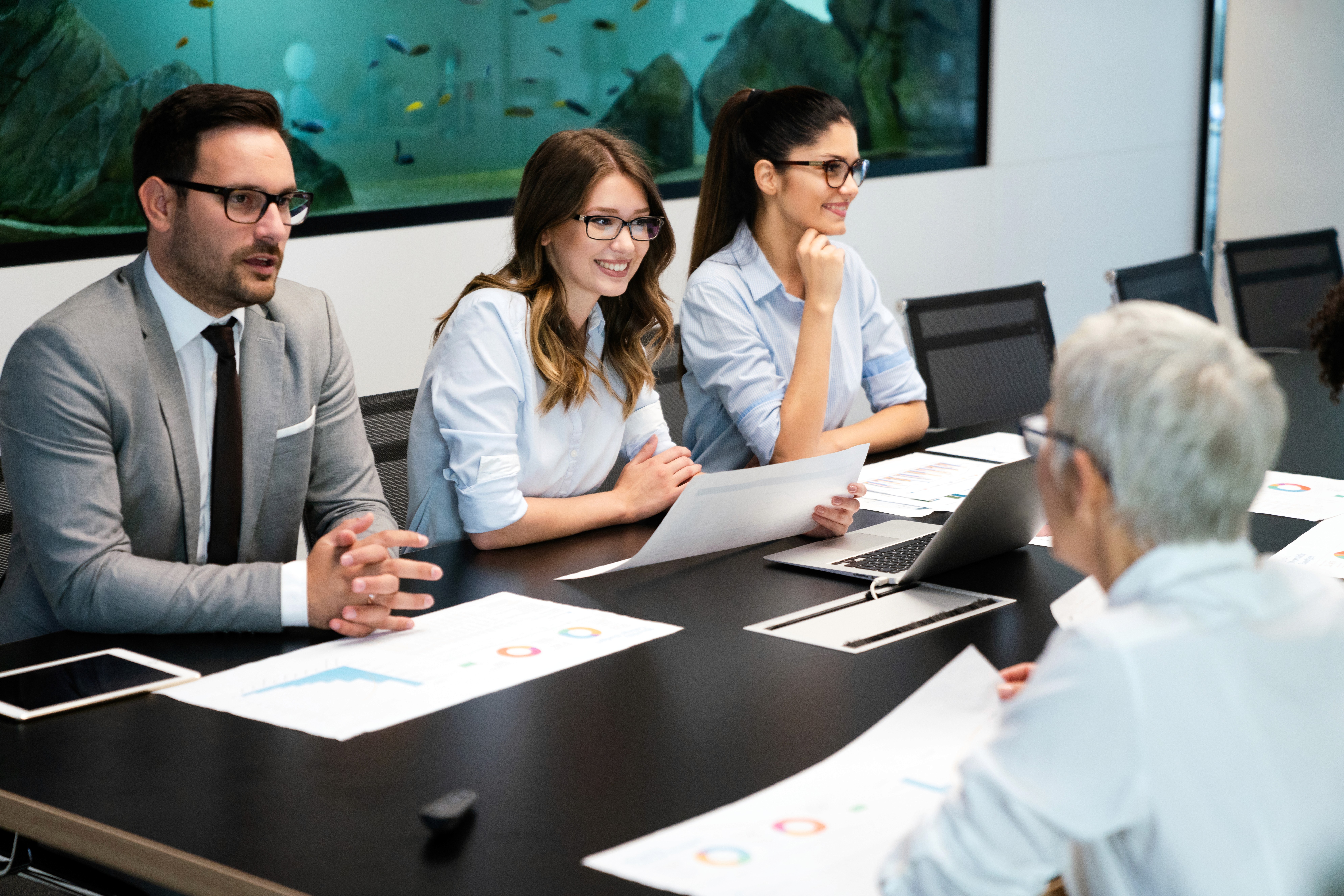 A woman in a striped shirt holds a credit card while using a laptop, bathed in warm sunlight in a cozy, modern setting.