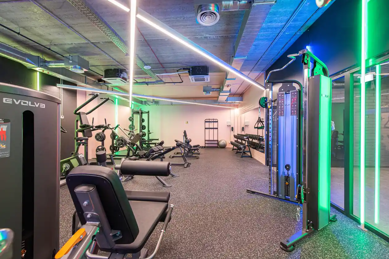 Modern fitness room in Vilnius student accommodation with weight machines, benches and free weights.