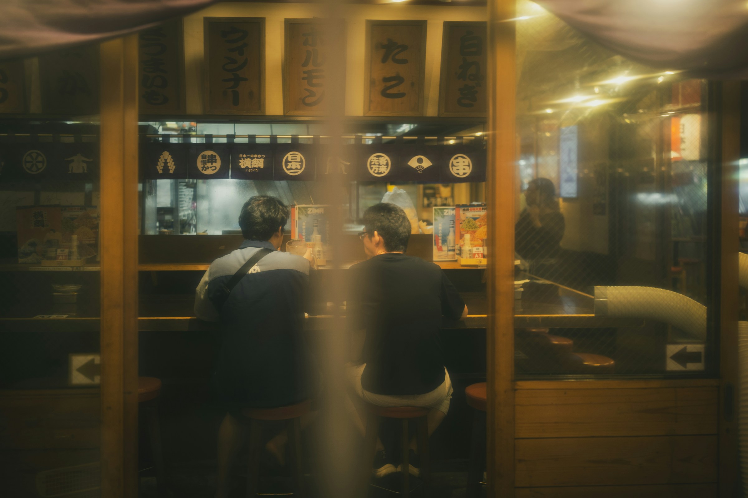 Two guests eating at a ramen counter late at night
