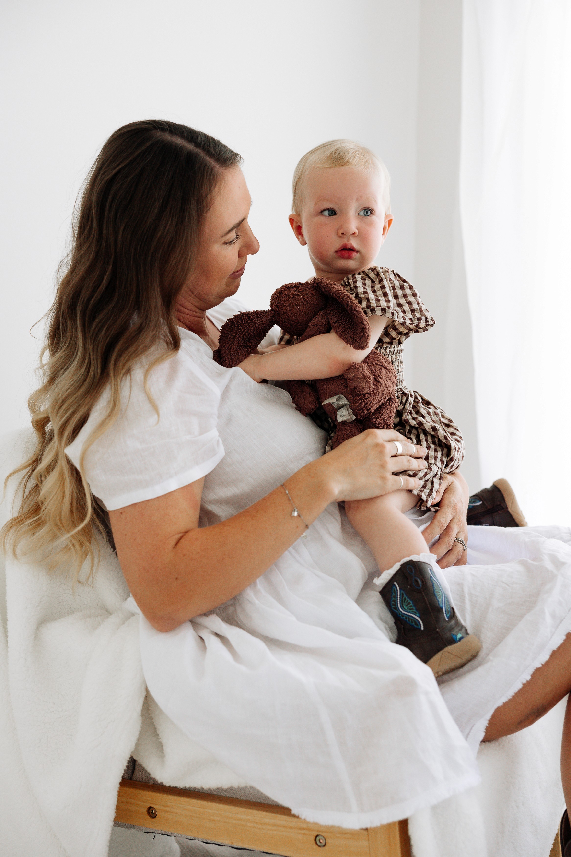 Intimate maternity session featuring an expecting mother cuddling her little girl in a neutral toned studio setting in Mackay, QLD