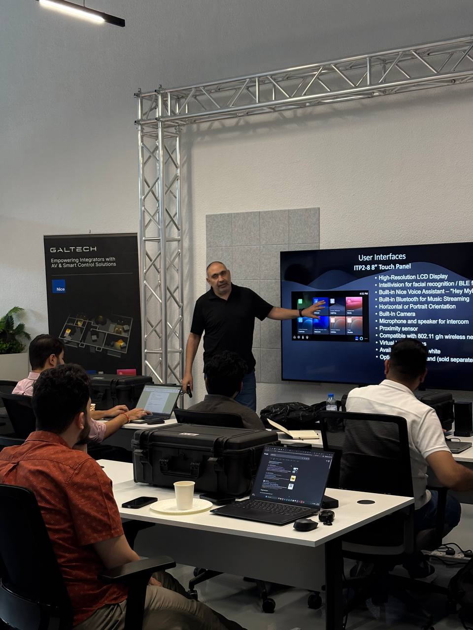 Man presents to people at tables with laptops.