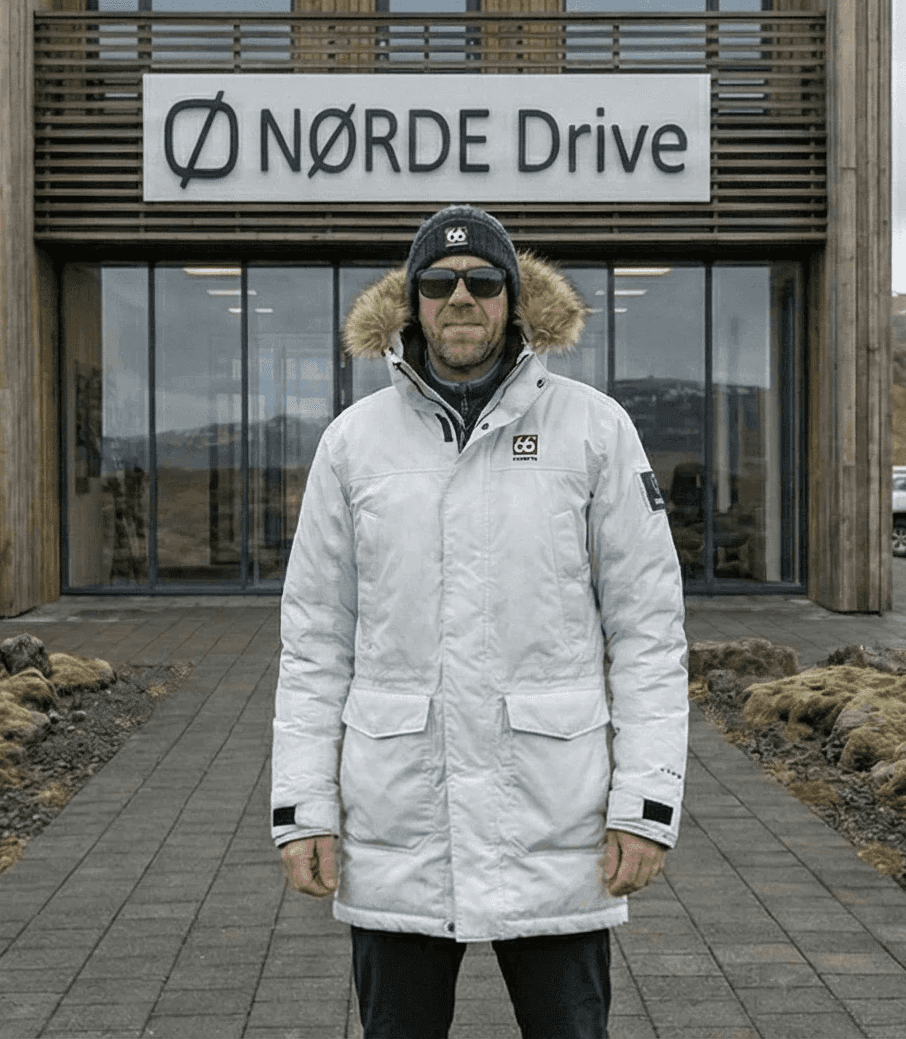 Man in a white parka standing in front of a modern building.