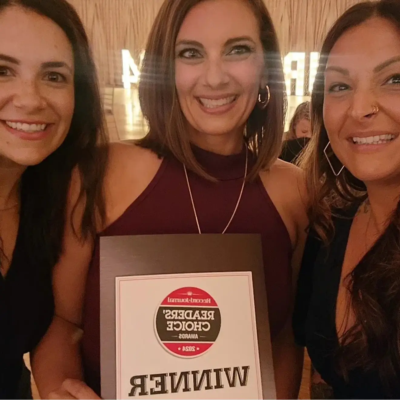 Three women celebrate holding a Record-Journal Readers' Choice Awards 2021 winner plaque.