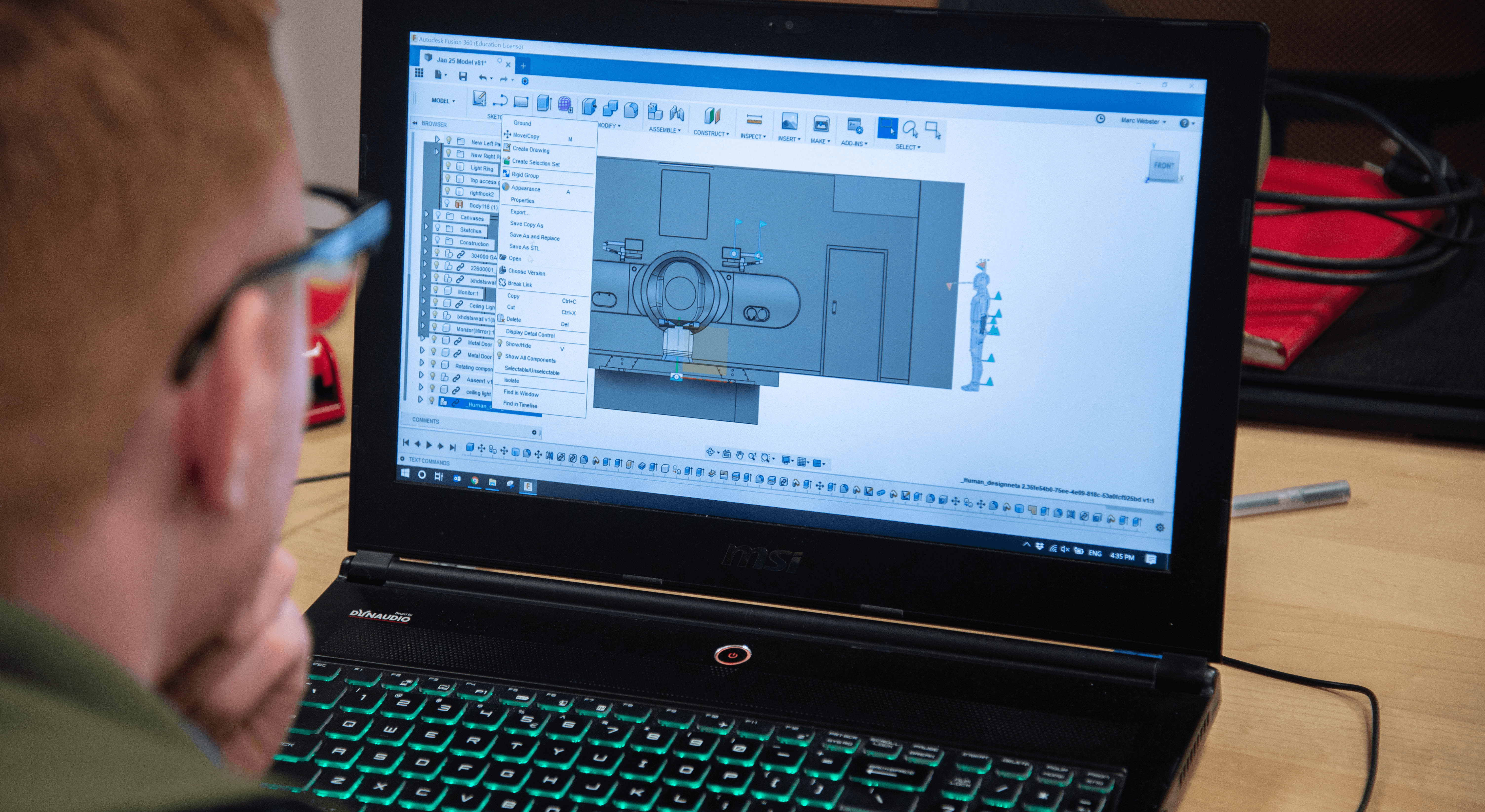 a person looking at a CAD model of a MRI machine on a laptop