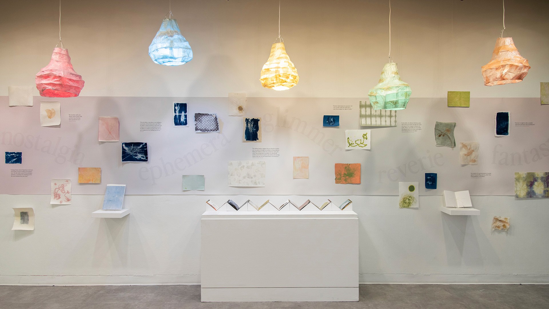 colorful lamps and artwork on the wall of a white gallery